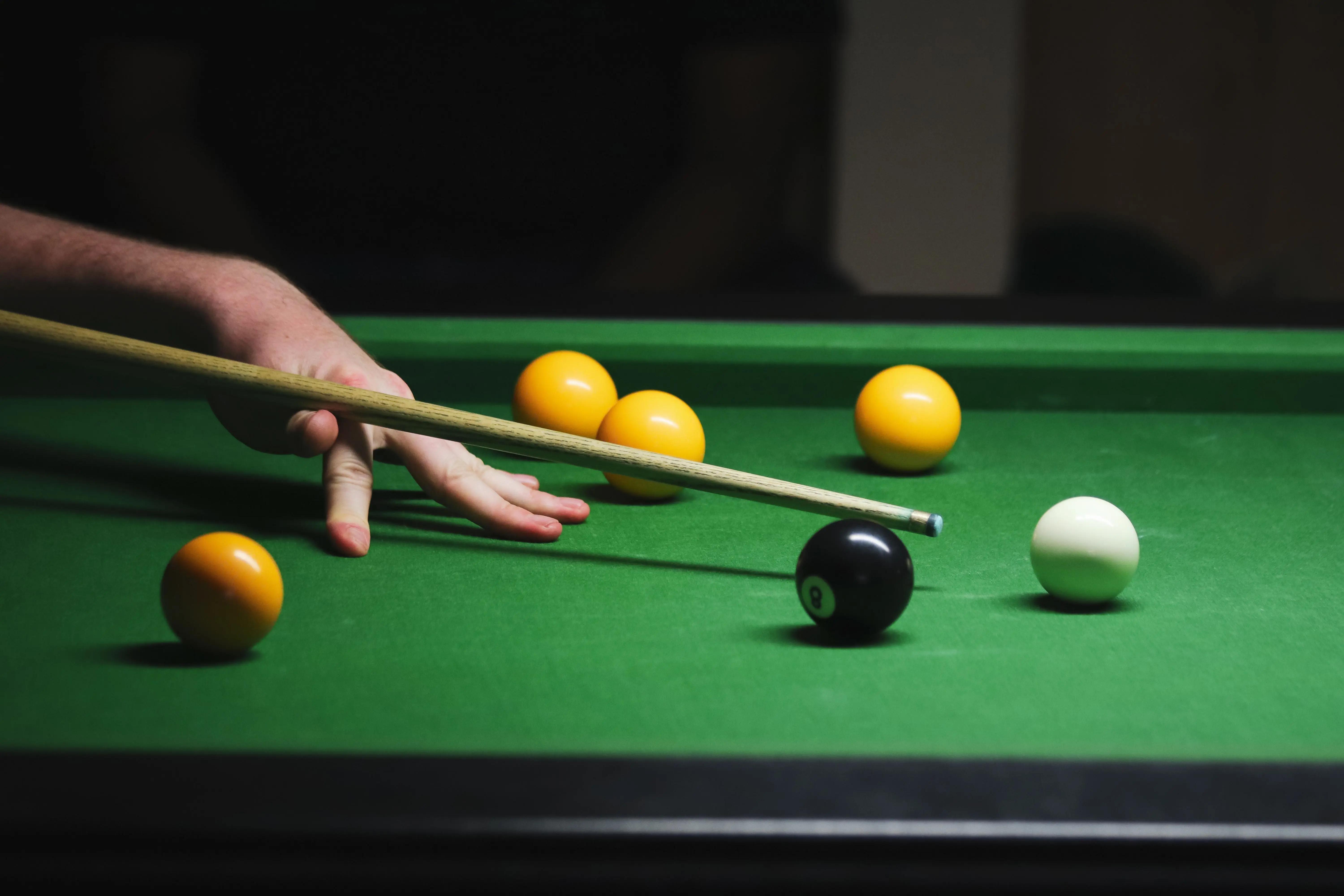 Player lining up a shot on a dark pool table